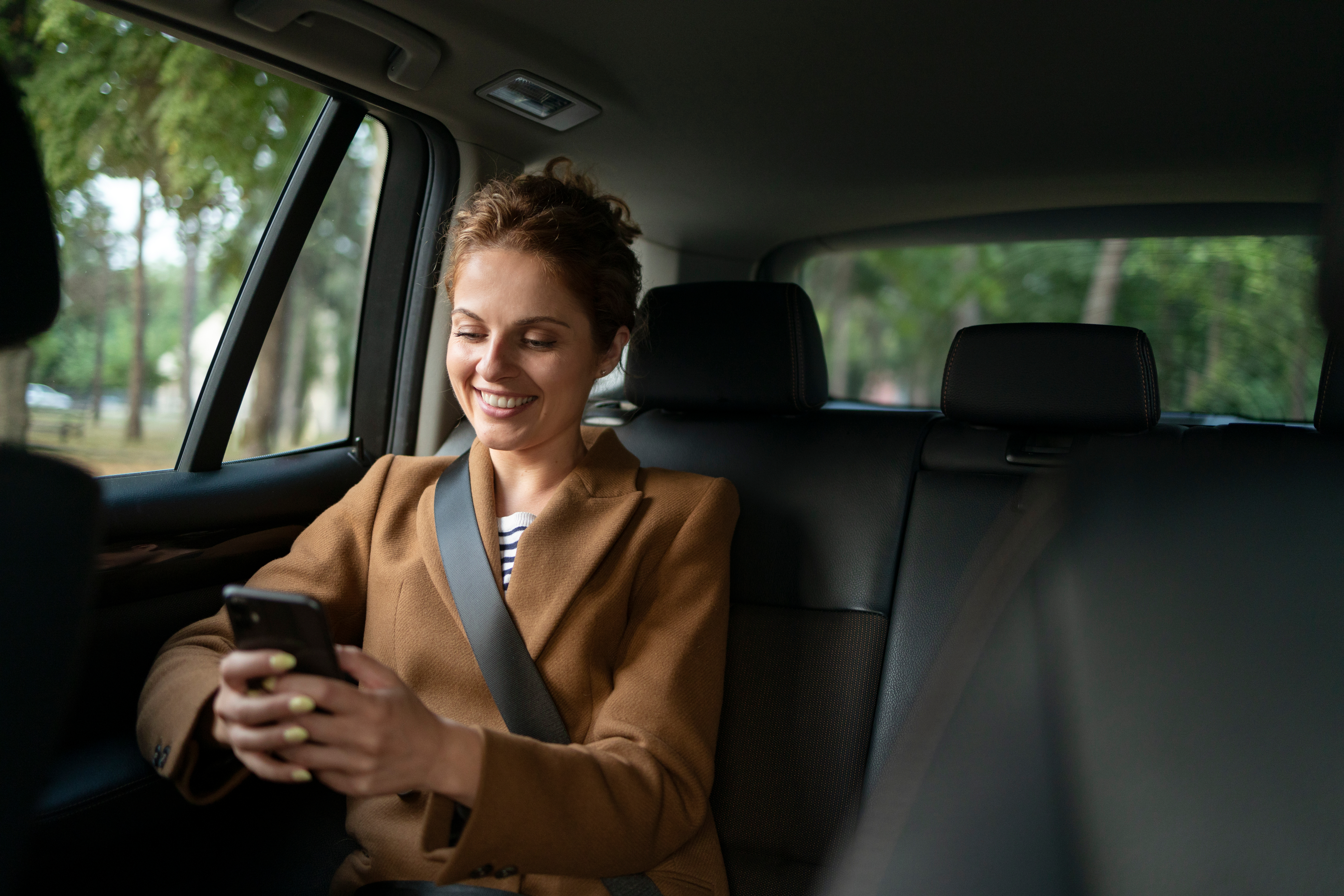 Passageira feliz utilizando smartphone dentro do veículo elétrico Reuel